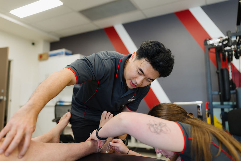 Exercise physiologist assisting a client with a strength and mobility exercise at Enable Exercise